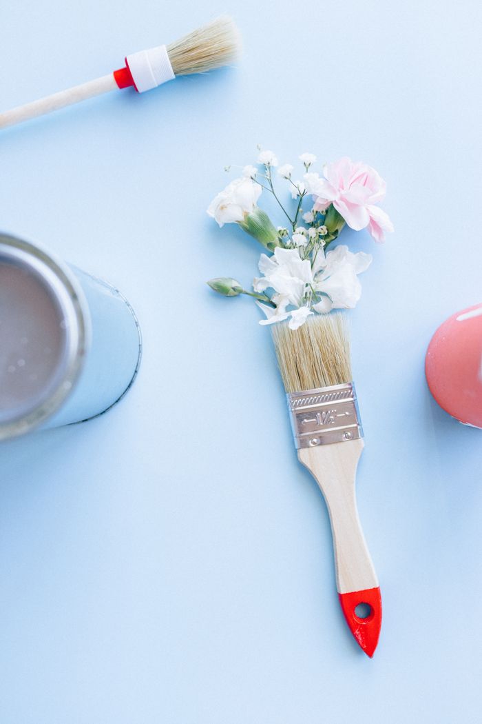 Floral decor with white and pink flowers on a paintbrush set against a light blue background.